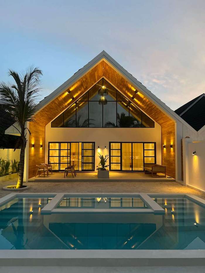 Villa lit up at night behind its pool